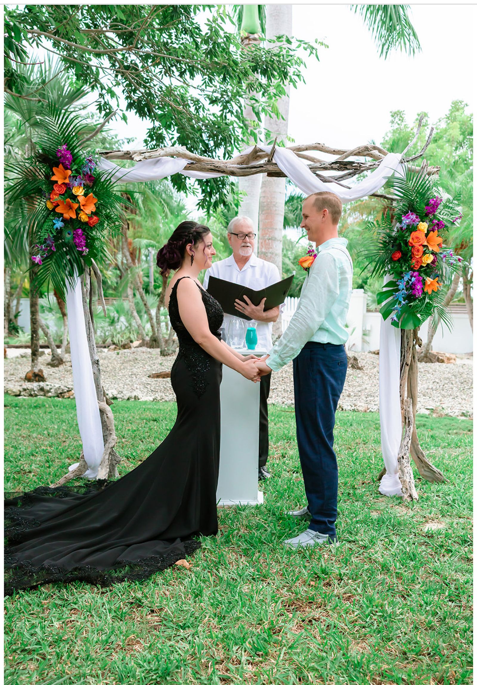 Couple exchanging vows beneath the driftwood arch at Pelico Palms